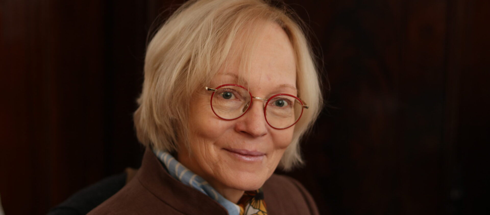 Porträt der Steuerberaterin Elisabeth Hess, lächelnd und professionell, mit einer runden, roten Brille